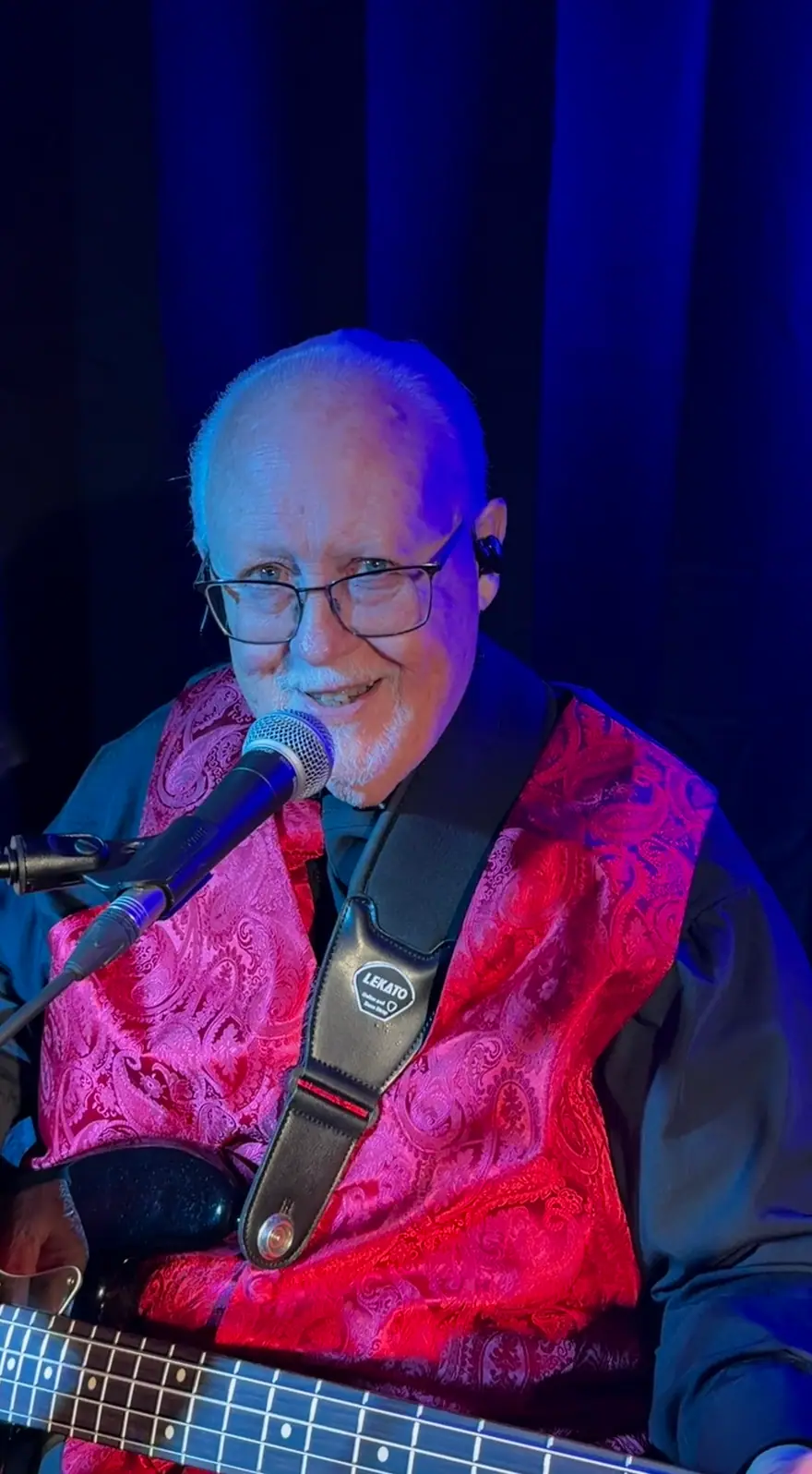 Ventura Band bassist in a red paisley vest smiling into a microphone