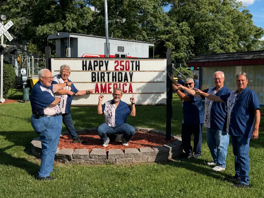 The Ventura Band gathered around a sign reading Happy 250th Birthday America