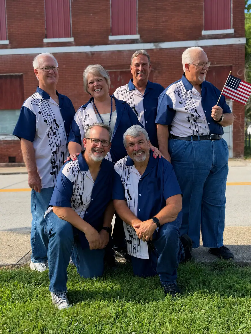 Members of The Ventura Band posing beside a brick building with an American flag
