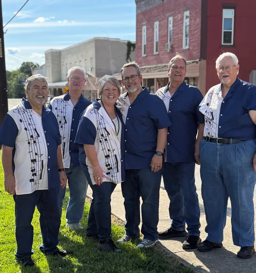 Members of The Ventura Band standing on a sidewalk beside a red brick building