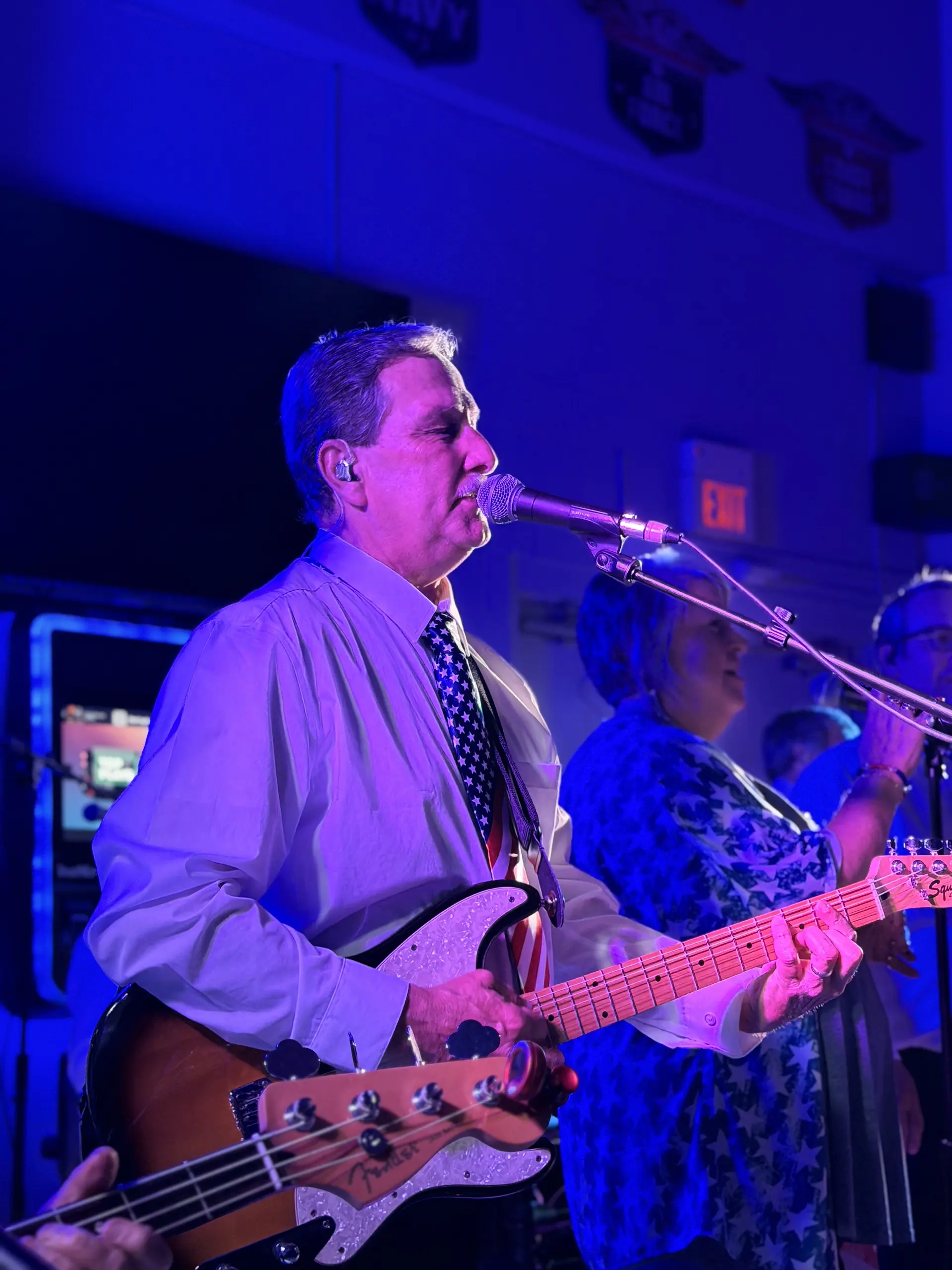 Ventura Band vocalist singing, with the bassist beside her under stage lights