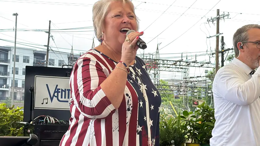Ventura Band singer in a stars-and-stripes top singing into a microphone