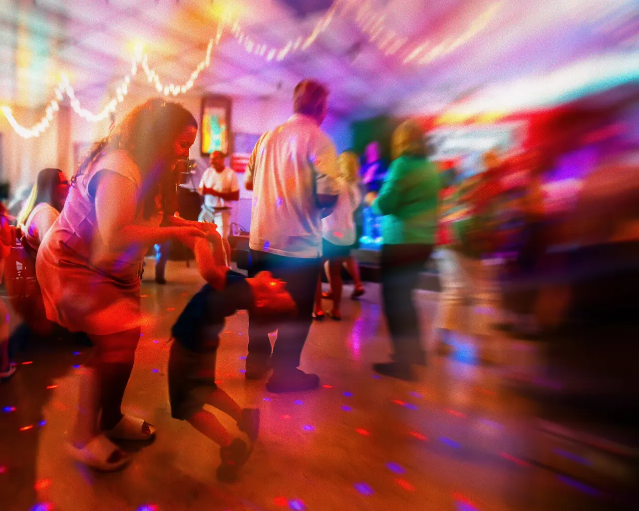 Couples dancing on a floor lit in red, blue, and purple